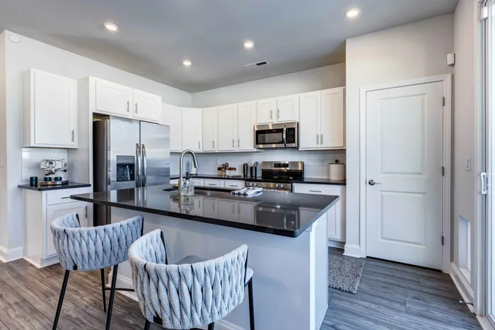 Kitchen area with island bar seating, tall ceilings, and stainless steel