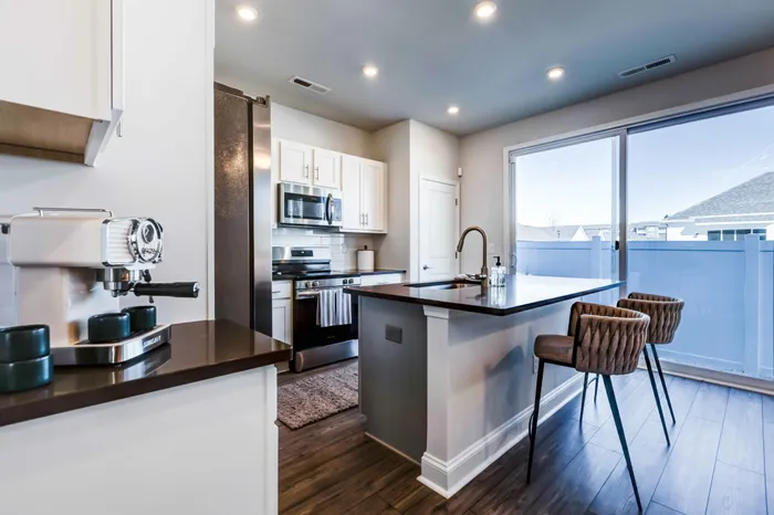 Kitchen area featuring quartz countertops, white cabinetry, kitchen island, and large sliding glass door