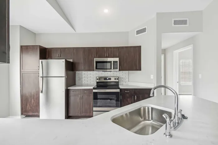 kitchen with stainless steel appliances and dark cabinetry alister sunset valley apartment homes for rent in austin tx