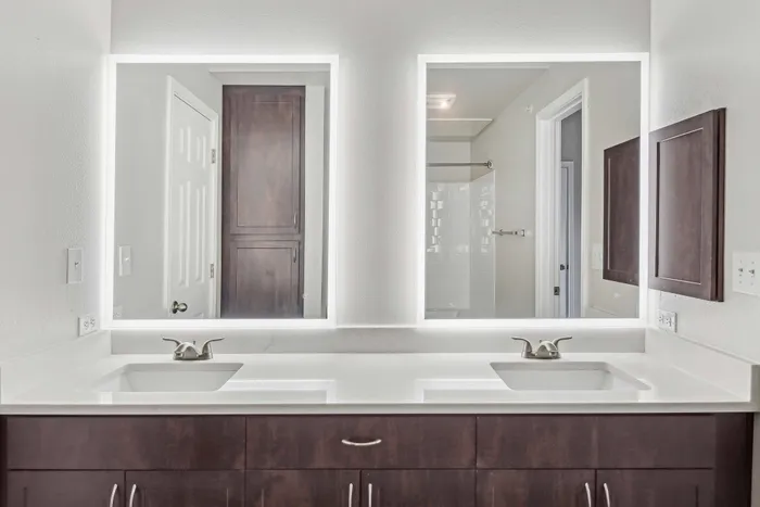 double vanity bathroom with light countertops and dark cabinets alister sunset valley apartment homes for rent in austin tx