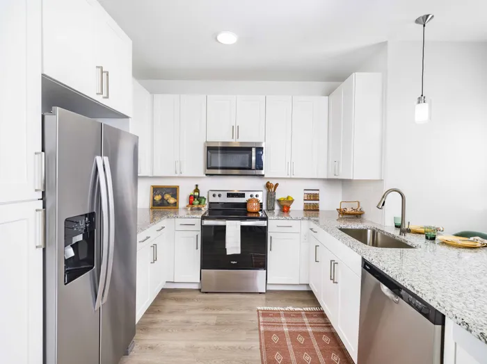 Large kitchen with custom white cabinetry, quartz countertops, and stainless steel appliances