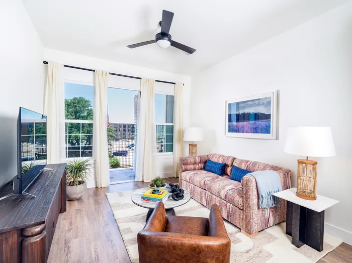 living room with hardwood style flooring large black ceiling fan and oversized windows