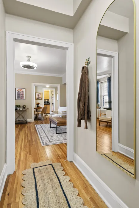 Charming entry hallway with hardwood floors leading to a cozy living room, featuring elegant decor and warm natural light.