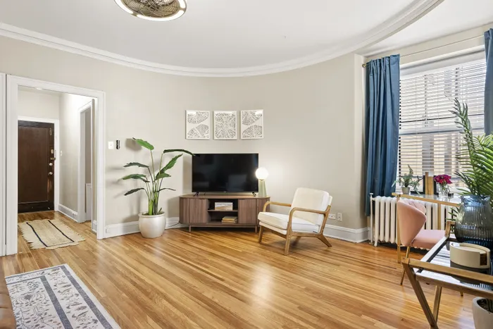 Elegant living room with gleaming hardwood floors, stylish mid-century modern furniture, and abundant natural light.