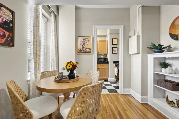 Charming dining nook with natural light, stylish wicker chairs, and vibrant floral decor, leading into a cozy kitchen with modern appliances.