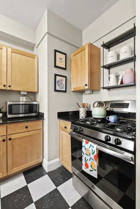 Charming kitchen with modern appliances, light wood cabinetry, and stylish black countertops in a cozy setting.