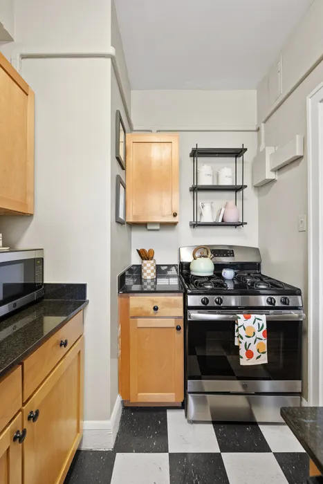 Charming kitchen with sleek black countertops, stylish wooden cabinets, and modern appliances enhanced by vibrant decor.
