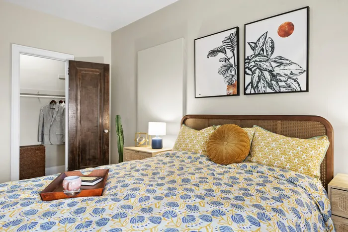Charming bedroom with vibrant decor, featuring a stylish patterned bedspread, modern art, and a cozy atmosphere.