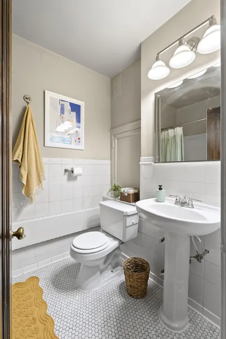 Charming bathroom with elegant white fixtures, hexagonal tile flooring, and stylish wall decor for a cozy ambiance.