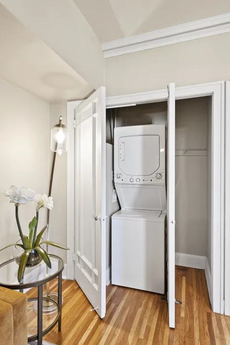 Chic apartment with in-unit stacked washer and dryer, elegant lighting, and stylish decor on warm hardwood floors.