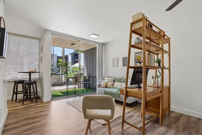 Bright and inviting living space with sleek wood floors, cozy seating area, and modern decor, seamlessly opening to a lush outdoor patio.