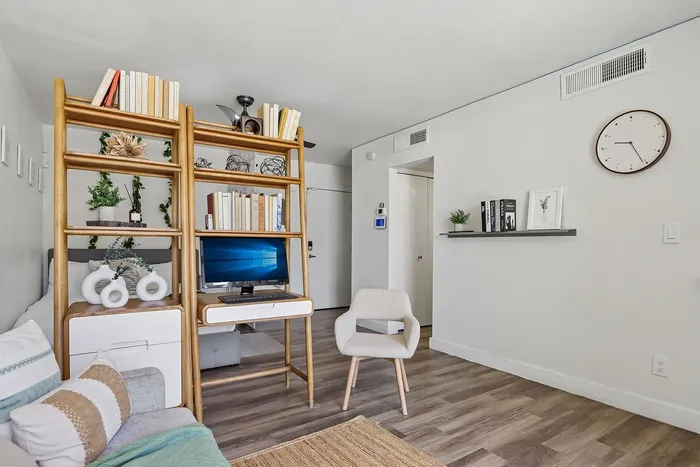 Chic living space featuring a stylish wooden bookshelf with books and decor, a cozy lounge chair, and inviting natural light.
