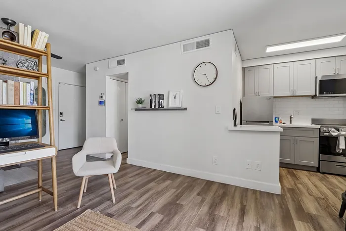 Modern apartment interior featuring a sleek kitchen with stainless steel appliances, cozy living area with stylish shelving, and elegant wooden flooring.