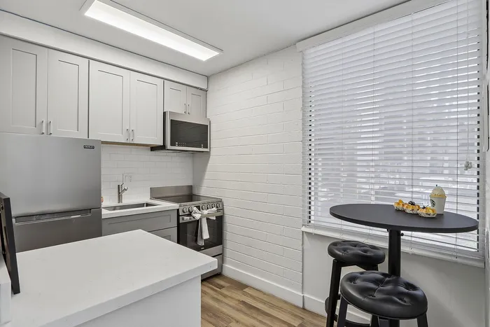 Chic modern kitchen with sleek appliances, stylish cabinetry, and cozy breakfast nook by large windows.