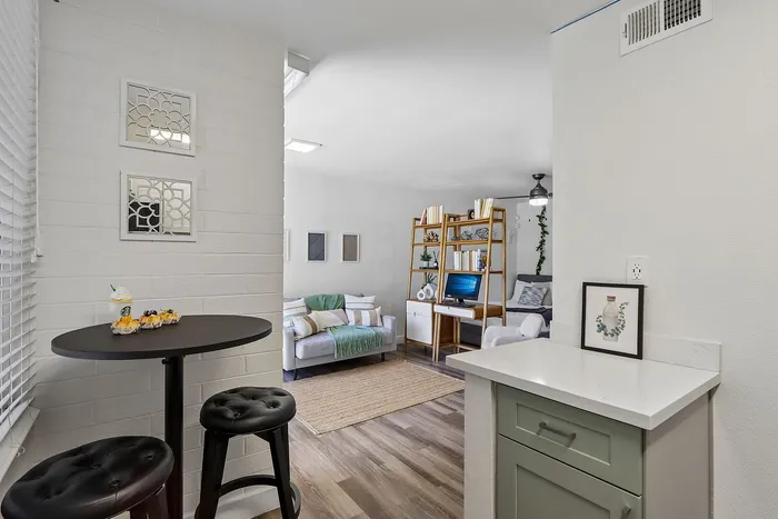 Cozy and stylish apartment interior featuring a modern living room with sleek shelving, a comfortable seating area, and a charming breakfast nook with black stools.