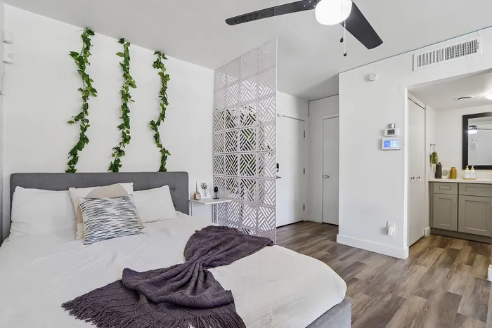 Bright and inviting bedroom with modern decor, featuring a cozy bed, stylish partition, and elegant green accent on the walls.