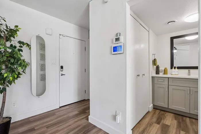 Modern apartment entryway showcasing sleek hardwood floors, a contemporary security system, and an inviting bathroom with stylish vanity.