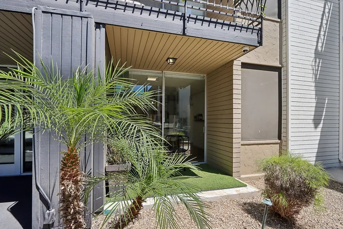 Inviting apartment entrance with lush greenery and glass door giving a modern touch.