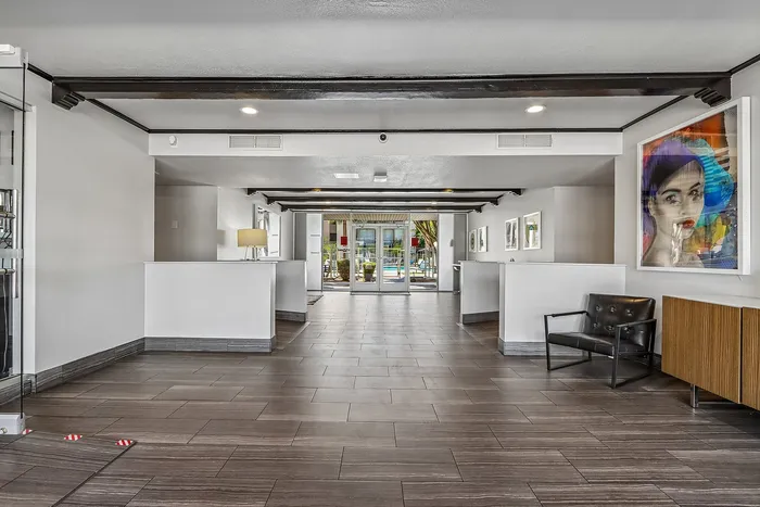 Bright and modern lobby with sleek tile flooring, contemporary artwork, and a view of the sparkling pool, offering a warm and inviting entrance.