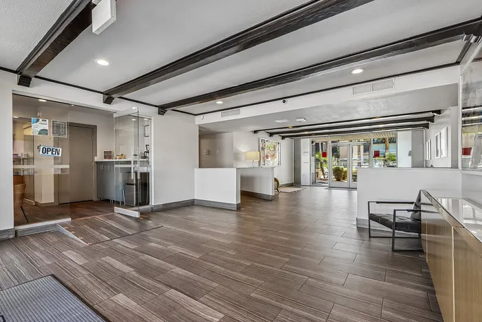 Modern apartment lobby with sleek tile flooring, exposed beams, and glass entryway offering a welcoming atmosphere.