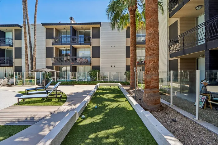 Chic apartment complex with modern balconies, surrounded by lush palm trees and a relaxing outdoor lounge area.