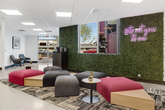 Chic and modern lounge area with vibrant seating, lush green wall, and neon sign for a vibrant ambiance.