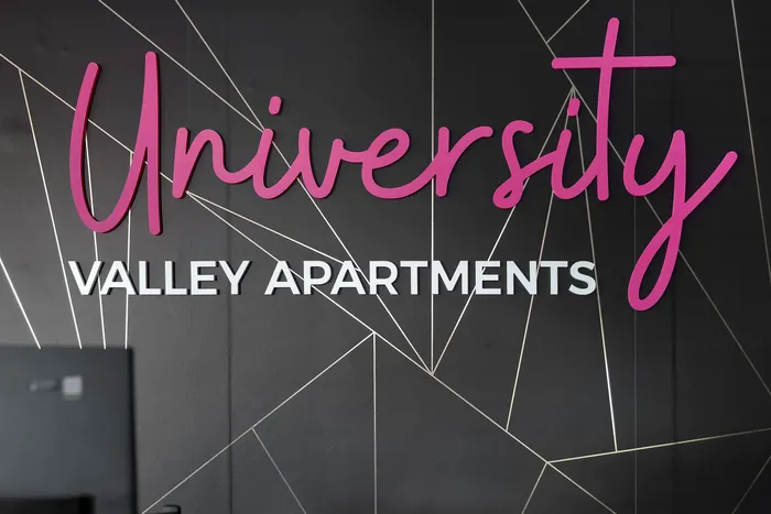 Chic University Valley Apartments sign with bold pink and white lettering on a stylish geometric background.
