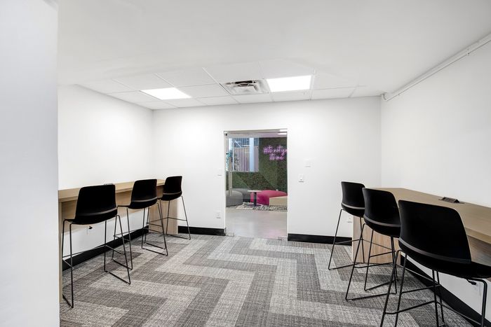 Modern workspace featuring sleek high chairs and a minimalist design with vibrant neon accents visible in the background.