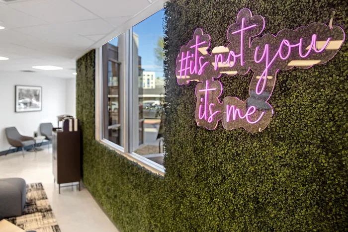 Modern apartment lobby featuring a trendy green wall with vibrant neon signage and sleek seating area.