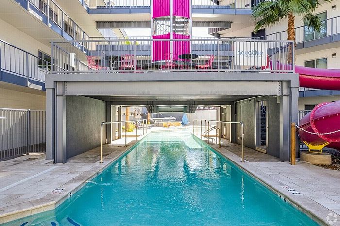 Inviting pool with modern architecture and vibrant pink accents, perfect for a refreshing swim at a stylish apartment complex.