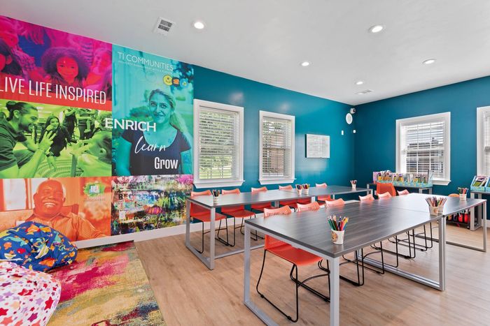 One-Bedroom Apartments in Laurel, MD - SouthRidge Apartments & Townhomes - Enrichment Center Classroom With Long Tables, Orange Chairs, Colorful Wall Mural, And Art Supplies By Bright Windows.