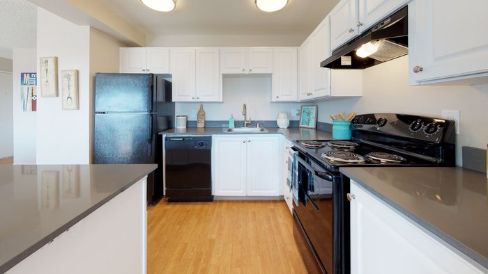 Renton WA Apartments - Sunset View - Kitchen with White Cabinets, Black Appliances, Wood Style Flooring, and Grey Countertops