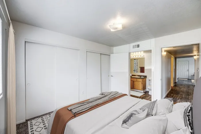 Two-Bedroom Apartments in North Las Vegas, NV - Portola Del Sol - Bedroom with Abstract Printed Bedding, Sliding Closet Doors, and Connected Bathroom