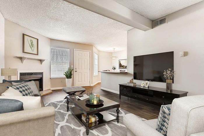 Aurora, CO, Apartments Near Downtown Denver - Silverbrook - Bright Living Room Featuring Dark Wood Floors, Cozy Fireplace, Wall-Mounted TV, And An Open Breakfast Bar Into The Kitchen.