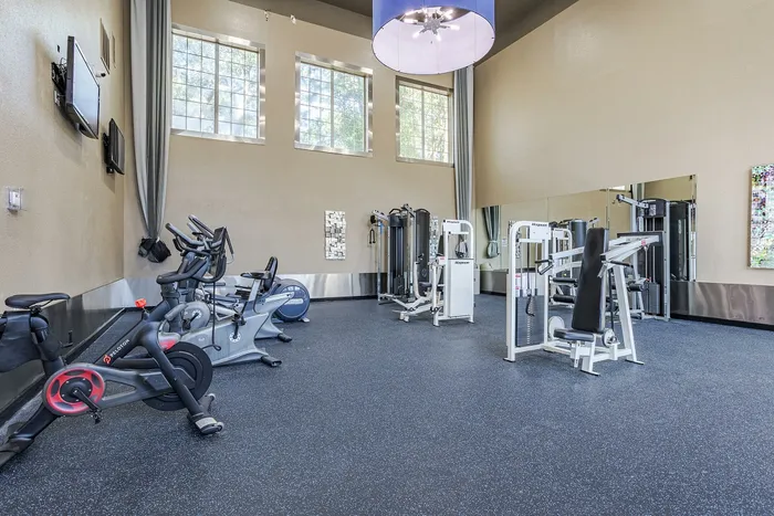 Westchase, TX, Apartments Near West Oaks Mall - Gramercy Park - A Fitness Center With Stationary Bikes, Elliptical Machines, Strength Training Equipment, Televisions, And Large Wall Mirror.