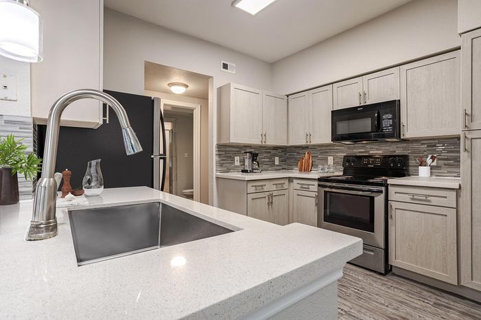 Westchase, TX, Apartments Near Beltway 8 - Gramercy Park - A Modern Kitchen With Light Wood Cabinets, Granite Countertops, And Undermount Sink With Gooseneck Faucet.