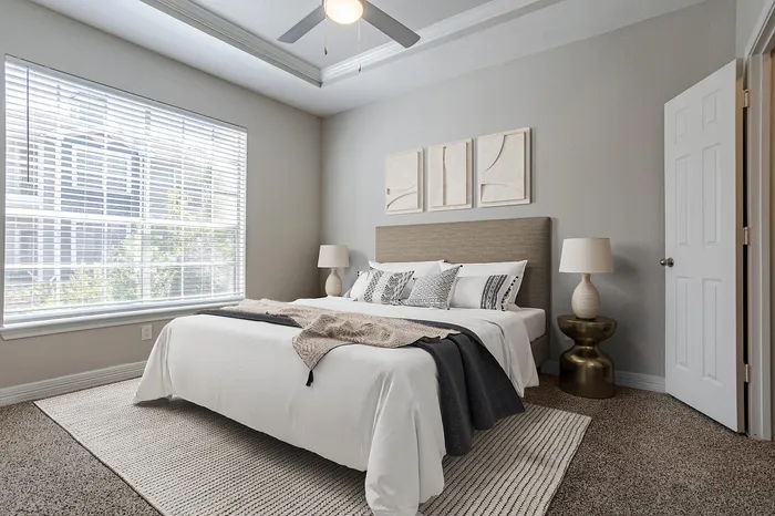 Dog-Friendly Apartments in Westchase, TX - Gramercy Park - A Bedroom With Matching Nightstands, Large Window With White Blinds, And Ceiling Fan.