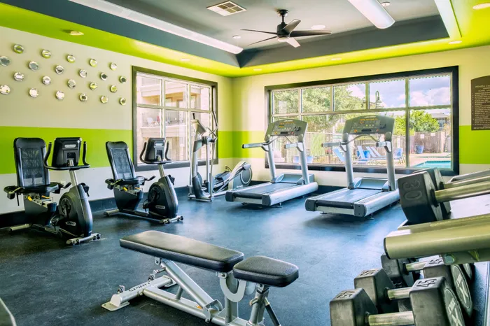 North Austin, TX, Apartments Near The Domain - Lotus Village Apartments - A Modern Fitness Center With Treadmills, Stationary Bikes, Weight Bench, And Dumbbells.