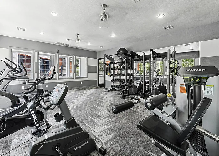 South Austin, TX, Apartments Near South Congress - Saratoga Ridge - Modern Fitness Center With Cardio Machines, Strength Training Station, Large Windows, And Bright Overhead Lighting.