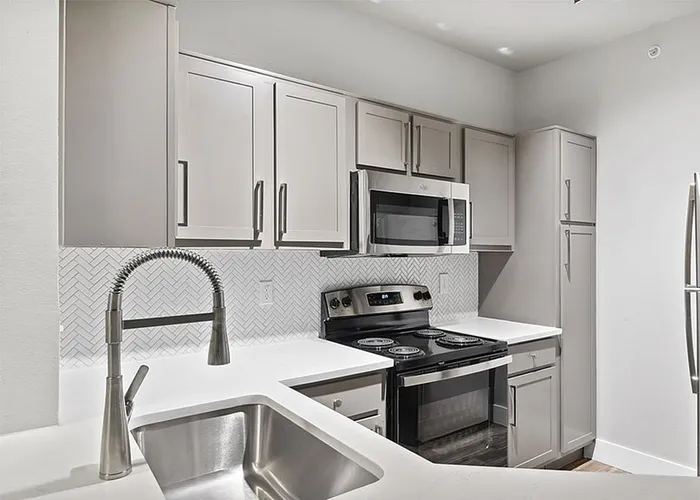 South Austin, TX, Apartments Near Southpark Meadows - Saratoga Ridge - Bright Modern Kitchen With White Quartz Counters, Gray Cabinets, Herringbone Backsplash, And Stainless Range.