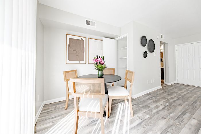 North Dallas, TX, Apartments Near Katy Trail - Ventana Apartment Homes - A Dining Area Features A Round Dark Table, Four Light Wood Chairs, And Gray Wood-Look Flooring.