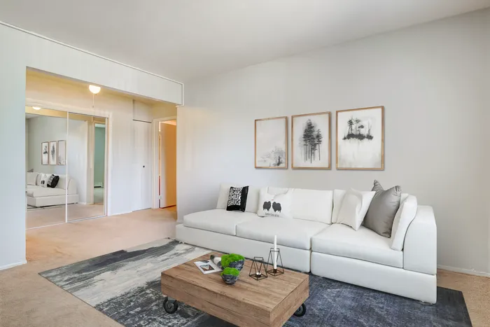 Glendale Heights, IL, Apartments Near Chicago O’Hare Airport - Ellyn Crossing Apartments - Living Room With Sofa, Round Coffee Table, Mirror, and Sliding Glass Door With Patio View.