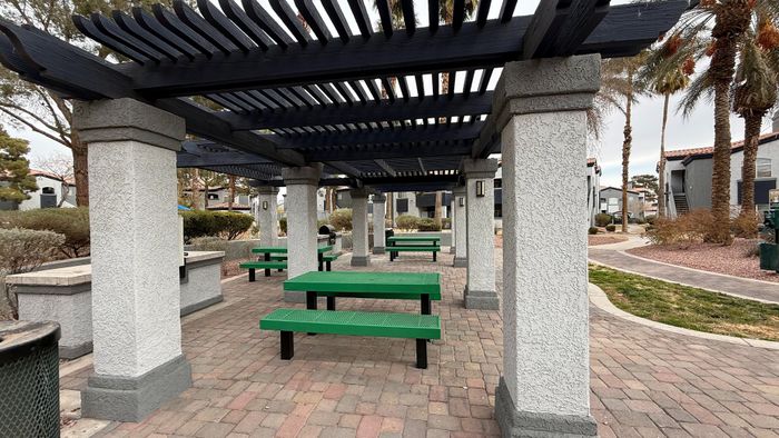 Inviting outdoor patio with green benches under stylish pergola surrounded by landscaped pathways.