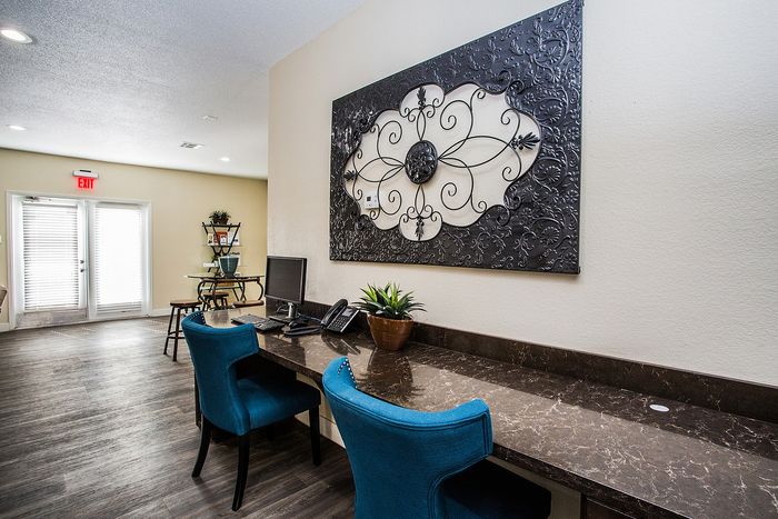 Elegant workspace with marble desk, blue chairs, and decorative wall art in a contemporary apartment setting.