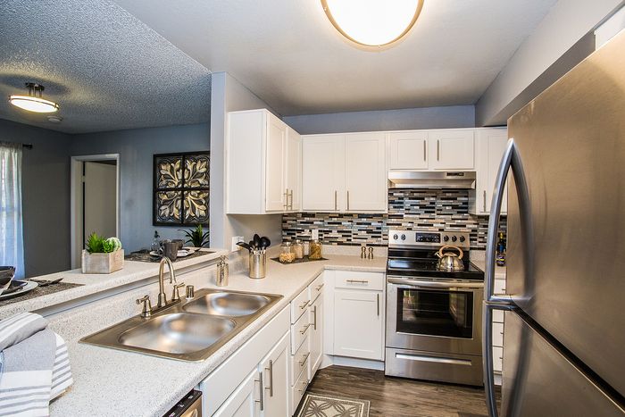 Elegant kitchen with white cabinetry, stainless steel appliances, and stylish backsplash.