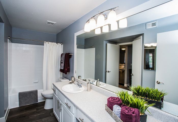 Modern bathroom with sleek white countertops, decorative plants, and soft lighting.