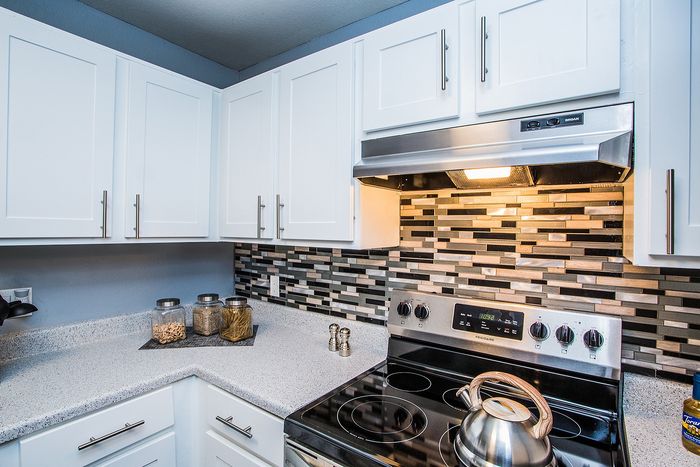 Contemporary kitchen with white cabinets, modern backsplash, and stainless steel appliances.