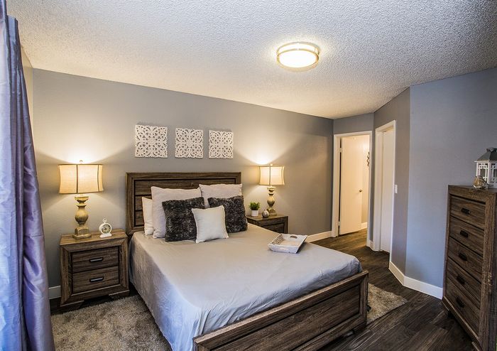 Chic bedroom with stylish decor, featuring a wooden bed frame, soft lighting, and modern furnishings.
