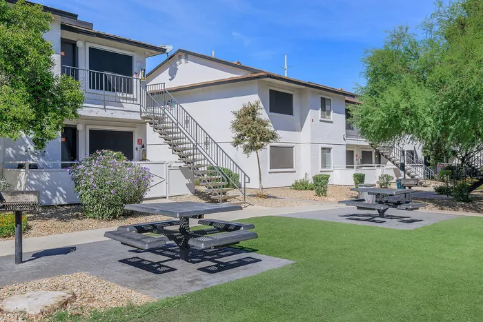 Modern two-story apartment complex with lush landscaping and outdoor seating areas.