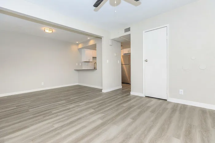 Bright open-concept space with modern flooring and kitchen view, featuring stainless steel appliances.